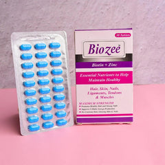 Biozee Biotin + Zinc supplement box and blister pack of blue tablets on pink surface